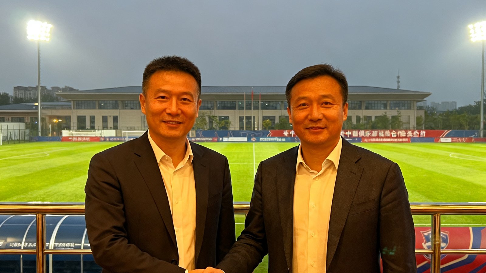 优发国际与某中超俱乐部战略合作签约仪式现场，双方代表握手合影，背景为俱乐部训练基地