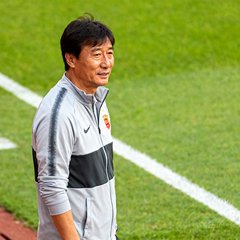 某中超职业足球俱乐部技术总监李教练，穿着训练服站在球场边线的半身照片